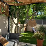 Aménager un petit jardin de 10m2 : salon de jardin confortable, fausse pelouse, arbre fruitier, paillasson décoratif et transat pour un coin détente.
