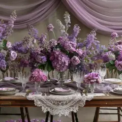 Magnifique table de mariage bohème ornée de bouquets de fleurs mauves et lilas, nappes en dentelle et tissus vaporeux.