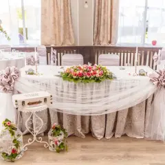Magnifique table de mariage champêtre ornée de fleurs roses et blanches, de voilages légers et de cages décoratives.