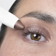 Application d'un fard à paupières bronze, couleur iris fleur, sur un œil.