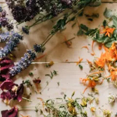 Comment faire sécher des fleurs avec de la laque : roses, lavande, et fleurs oranges séchées sur fond de bois.