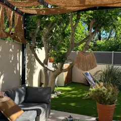 Aménager un petit jardin de 10m2 : salon de jardin confortable, fausse pelouse, arbre fruitier, paillasson décoratif et transat pour un coin détente.