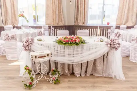 Magnifique table de mariage champêtre ornée de fleurs roses et blanches, de voilages légers et de cages décoratives.