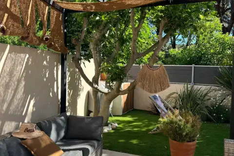 Aménager un petit jardin de 10m2 : salon de jardin confortable, fausse pelouse, arbre fruitier, paillasson décoratif et transat pour un coin détente.