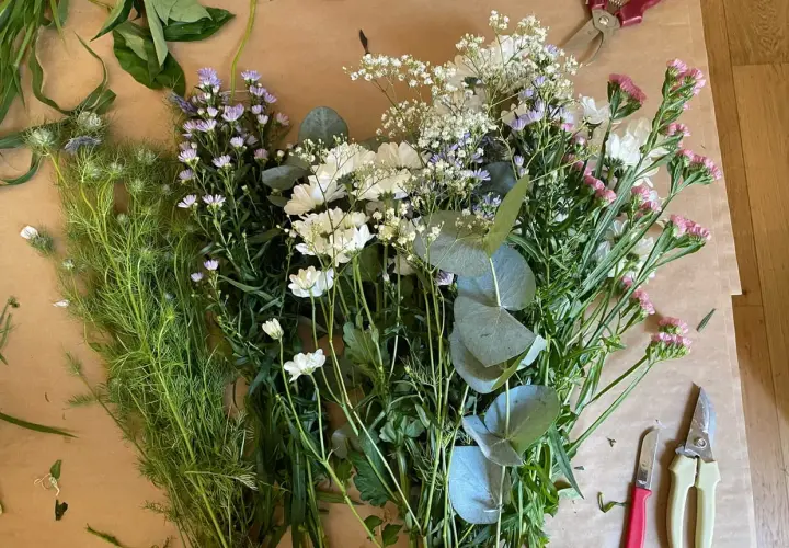 Un assortiment de feuillage pour bouquet, prêt à être assemblé. Des fleurs blanches, roses et violettes se mêlent à des feuilles d'eucalyptus.