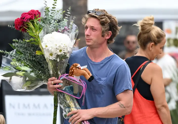 Un homme porte un bouquet de fleurs et une peluche de faon. Offrir des fleurs à un homme, signification : un geste d'affection ou de reconnaissance.