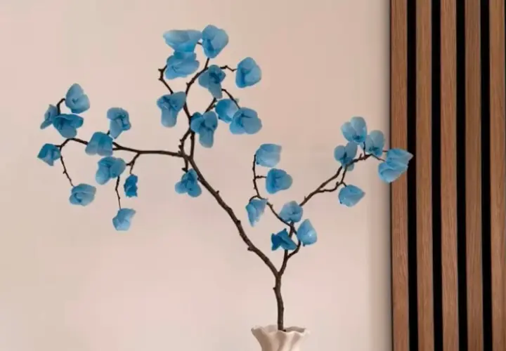 Une branche décorative avec des fleurs bleues en papier, une composition florale à faire soi-même.