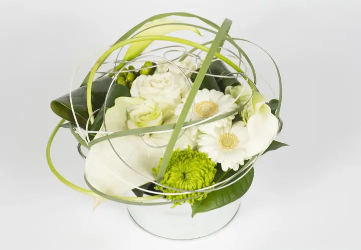 Une composition florale ronde, moderne et épurée, mêlant roses blanches, gerberas, callas et une touche de vert vif.