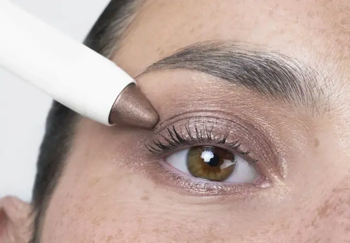Application d'un fard à paupières bronze, couleur iris fleur, sur un œil.