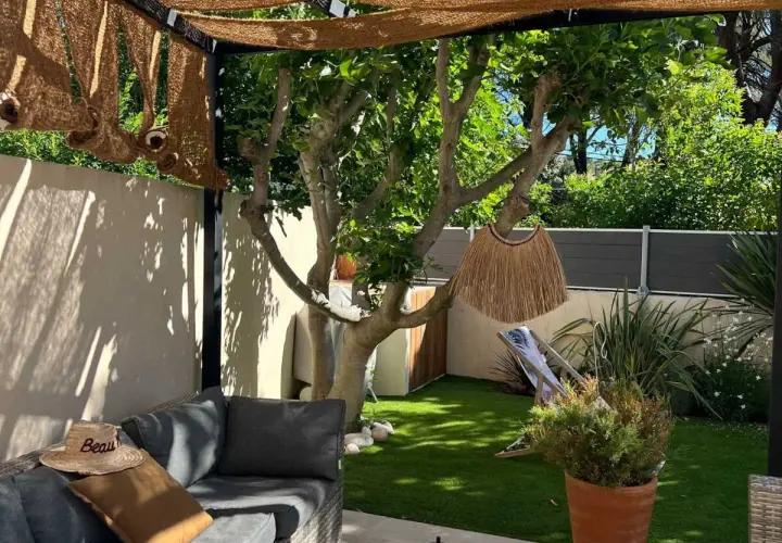 Aménager un petit jardin de 10m2 : salon de jardin confortable, fausse pelouse, arbre fruitier, paillasson décoratif et transat pour un coin détente.