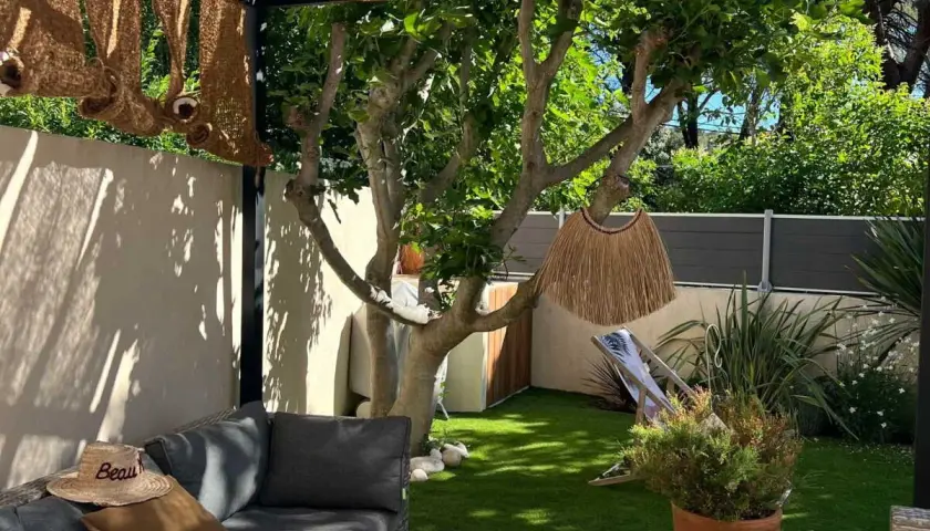 Aménager un petit jardin de 10m2 : salon de jardin confortable, fausse pelouse, arbre fruitier, paillasson décoratif et transat pour un coin détente.