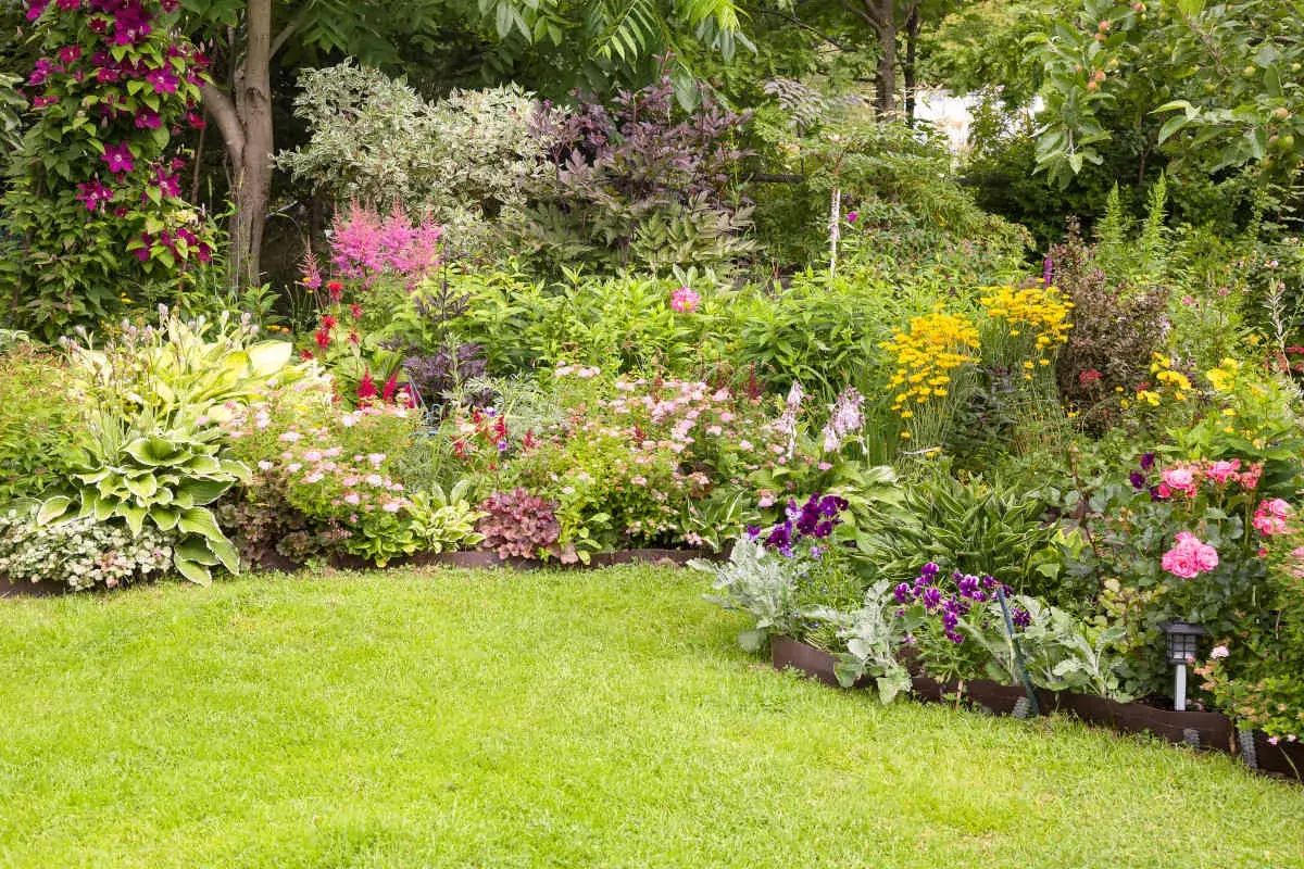 Un jardin luxuriant débordant de fleurs colorées, de roses roses, de digitales violettes et de marguerites jaunes.