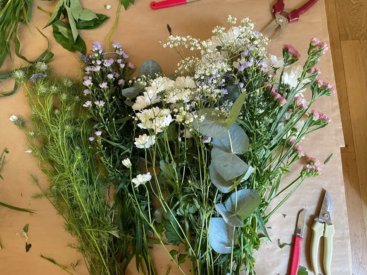 Un assortiment de feuillage pour bouquet, prêt à être assemblé. Des fleurs blanches, roses et violettes se mêlent à des feuilles d'eucalyptus.