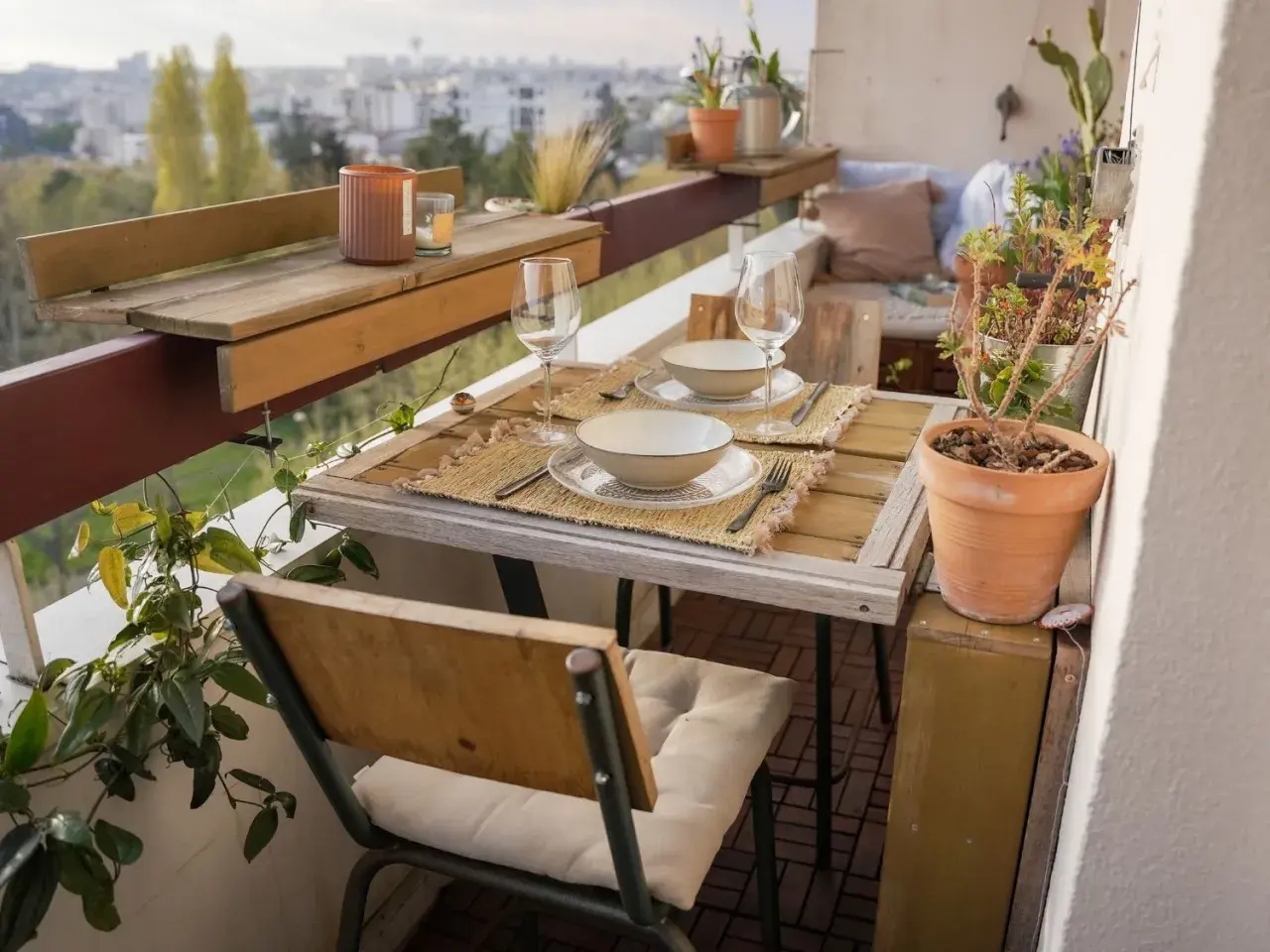 Jolie deco balcon avec table dressée pour deux, plantes vertes et vue sur la ville. Parfait pour un dîner romantique.