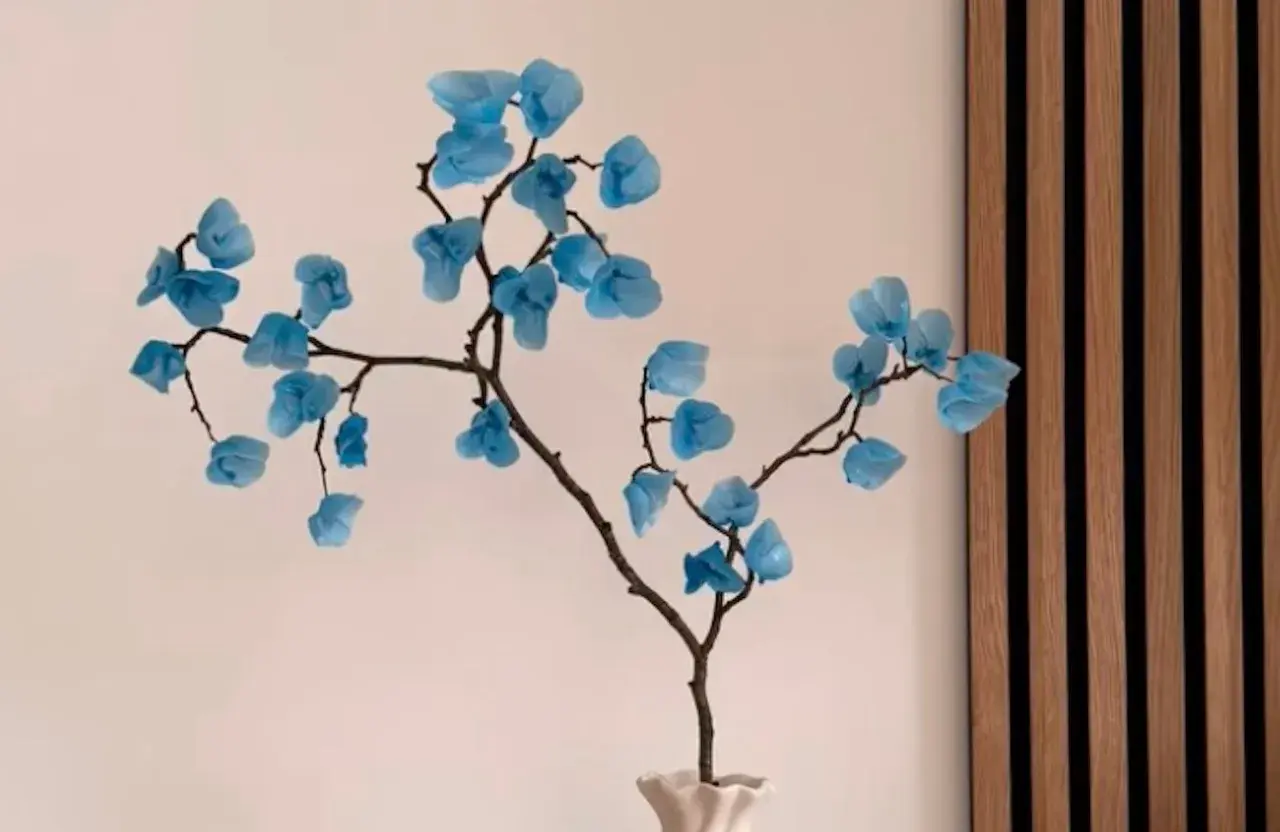 Une branche décorative avec des fleurs bleues en papier, une composition florale à faire soi-même.