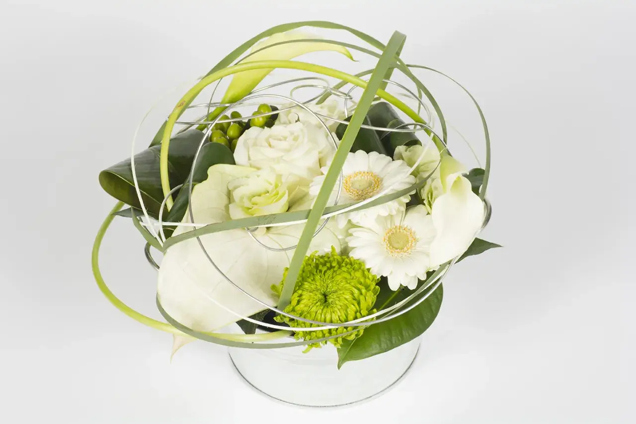 Une composition florale ronde, moderne et épurée, mêlant roses blanches, gerberas, callas et une touche de vert vif.