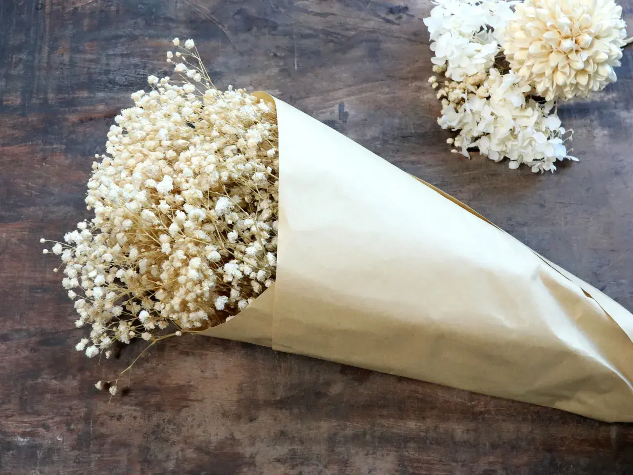 Un bouquet de gypsophile séché, emballé dans du papier kraft, prêt pour un projet de bricolage. Comment faire sécher du gypsophile.