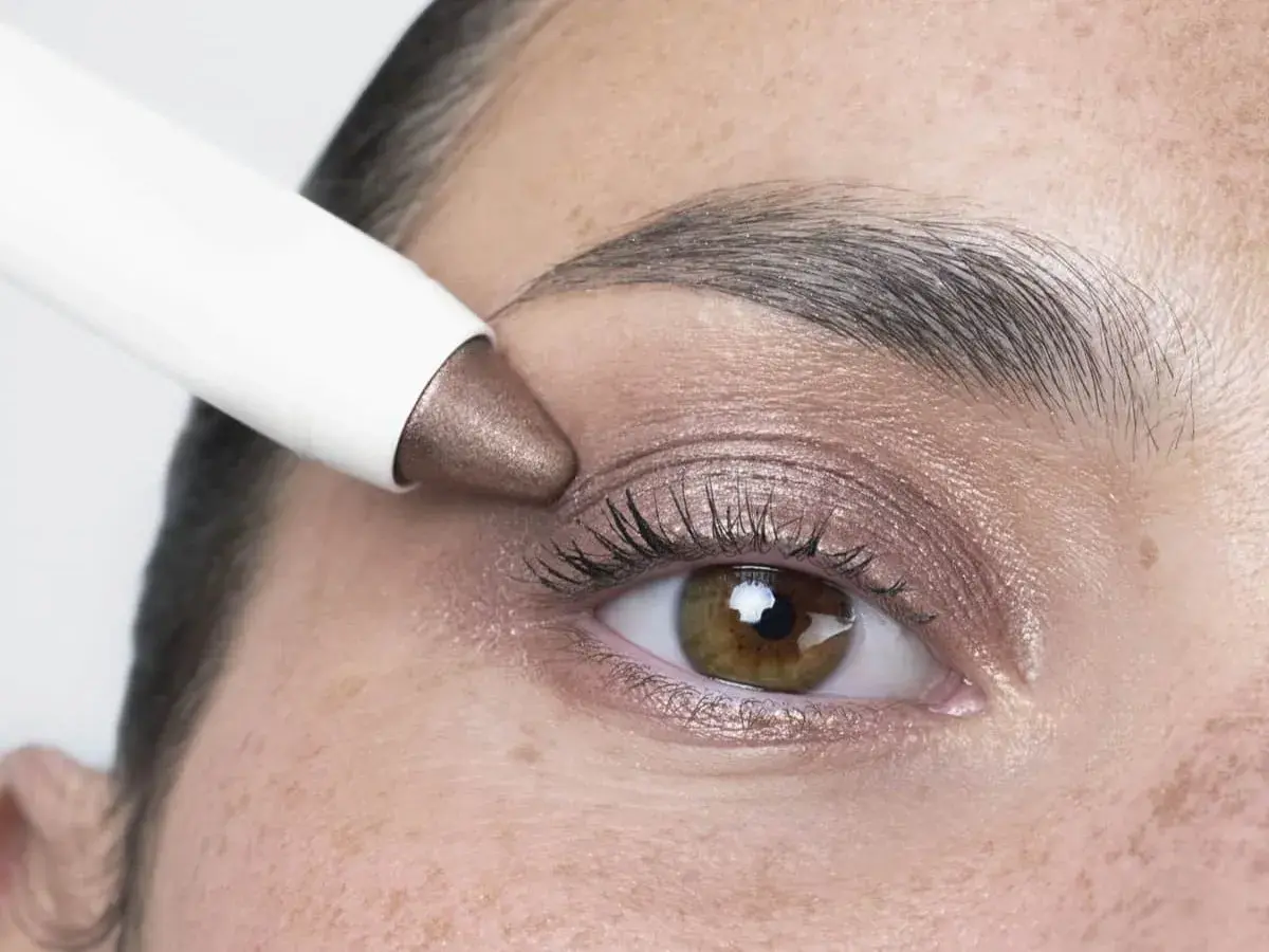 Application d'un fard à paupières bronze, couleur iris fleur, sur un œil.