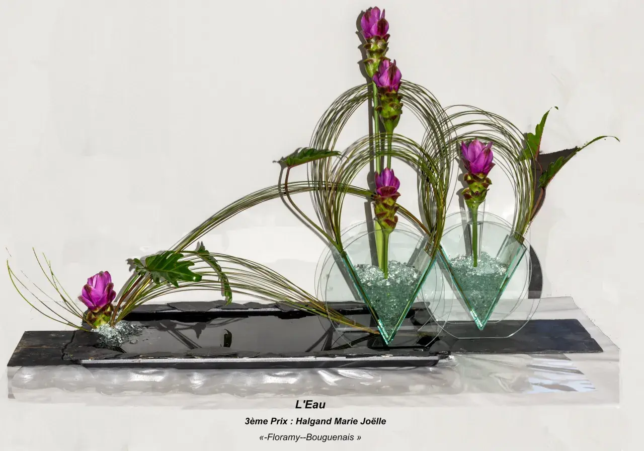 Composition florale en hauteur avec des fleurs roses et des feuillages verts, dans des vases en verre triangulaires.