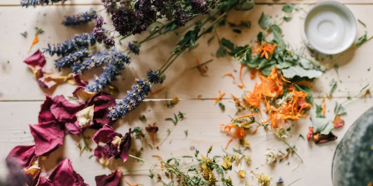 Comment faire sécher des fleurs avec de la laque : roses, lavande, et fleurs oranges séchées sur fond de bois.