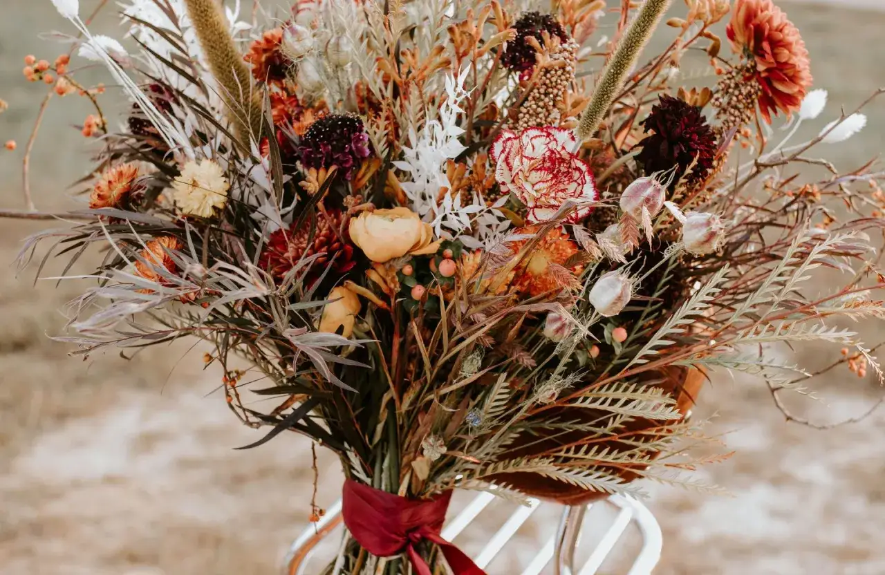 Magnifique bouquet de fleurs séchées aux tons chauds, parfait pour une décoration mariage automne. Des pampas, des dahlias et des baies orangées créent une ambiance rustique et élégante.