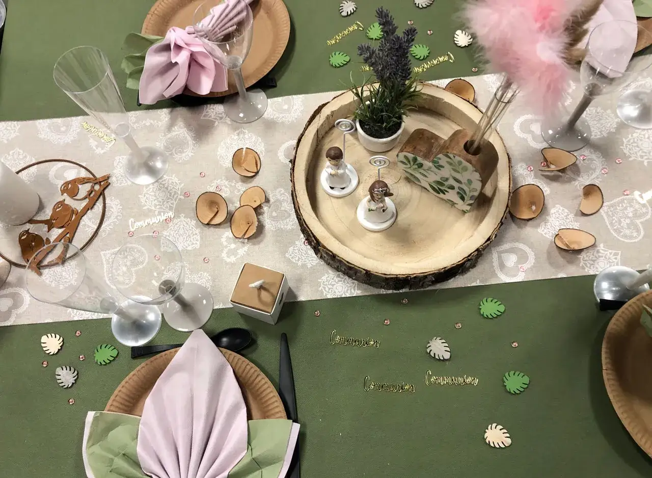 Jolie composition florale pour une communion, avec des figurines, des rondins de bois et des d&eacute;corations v&eacute;g&eacute;tales.