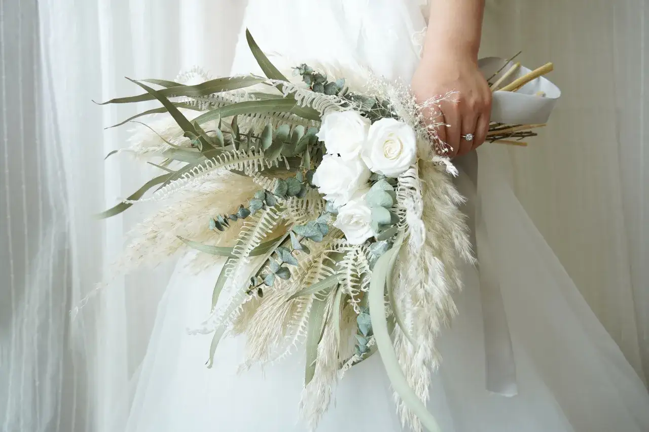 Un petit bouquet mariage civil, compos&eacute; de roses blanches, de pampas et d'eucalyptus, tenu par une mari&eacute;e.
