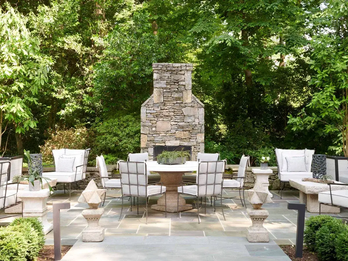 Un espace ext&eacute;rieur invitant avec chemin&eacute;e en pierre, table et chaises pour une d&eacute;coration v&eacute;randa ext&eacute;rieur parfaite.
