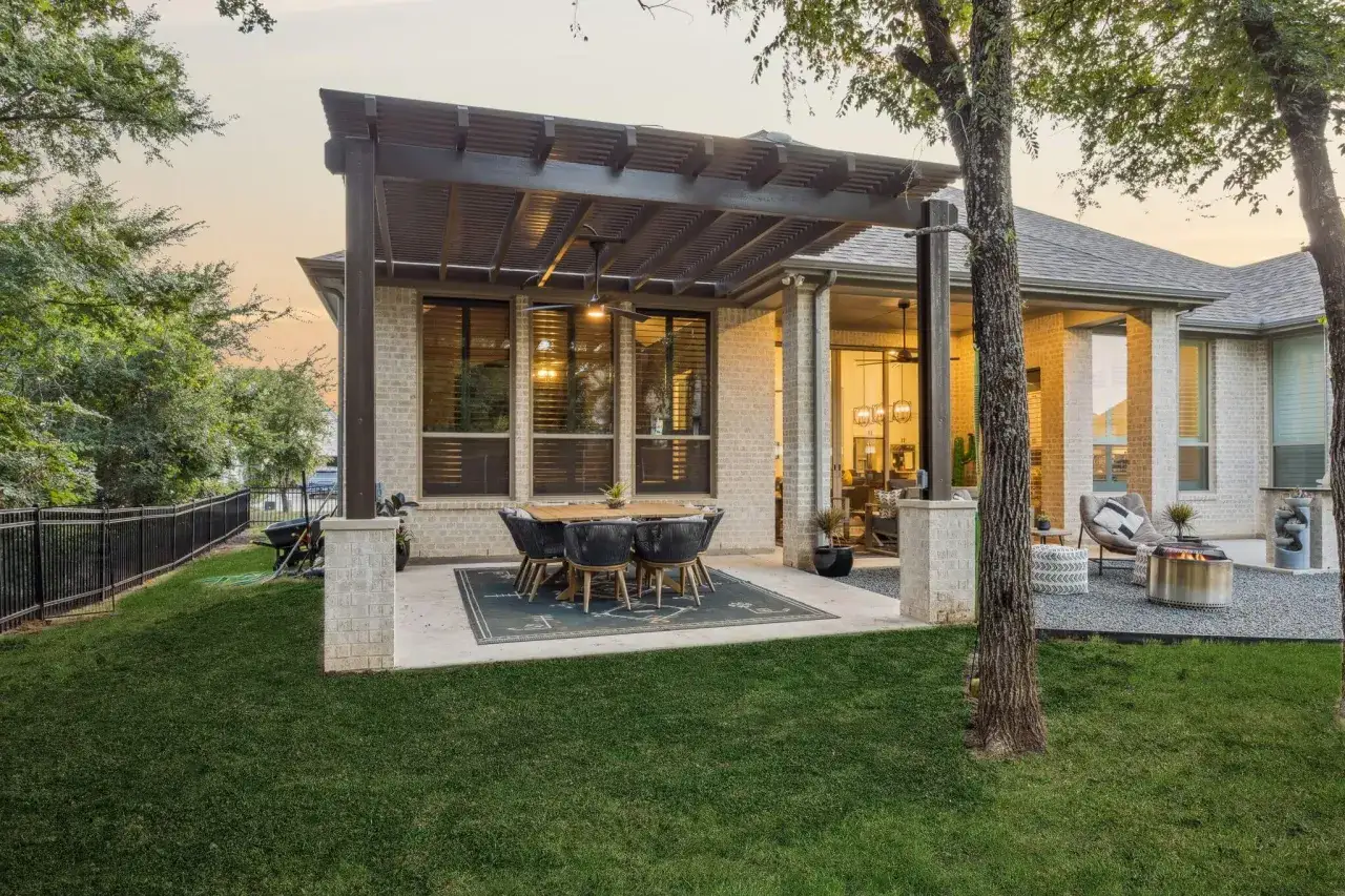 Table et chaises sous une pergola, parfaites pour la d&eacute;coration v&eacute;randa ext&eacute;rieur. Un feu de camp et des si&egrave;ges invitent &agrave; la d&eacute;tente.